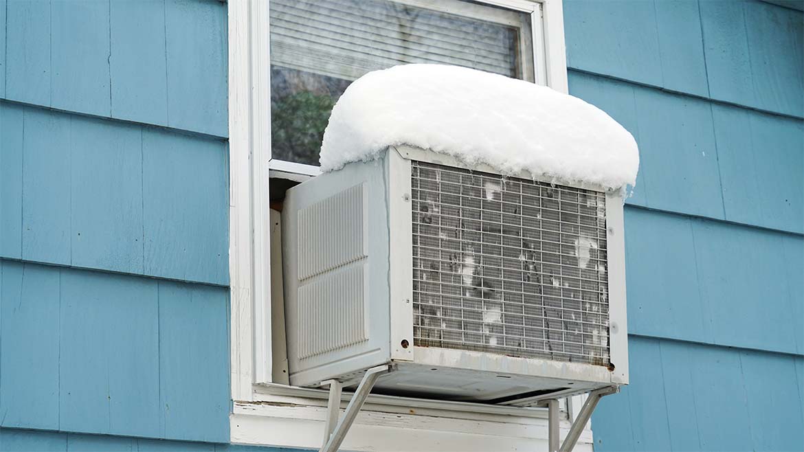 Window air conditioner from the outside in winder, covered in snow
