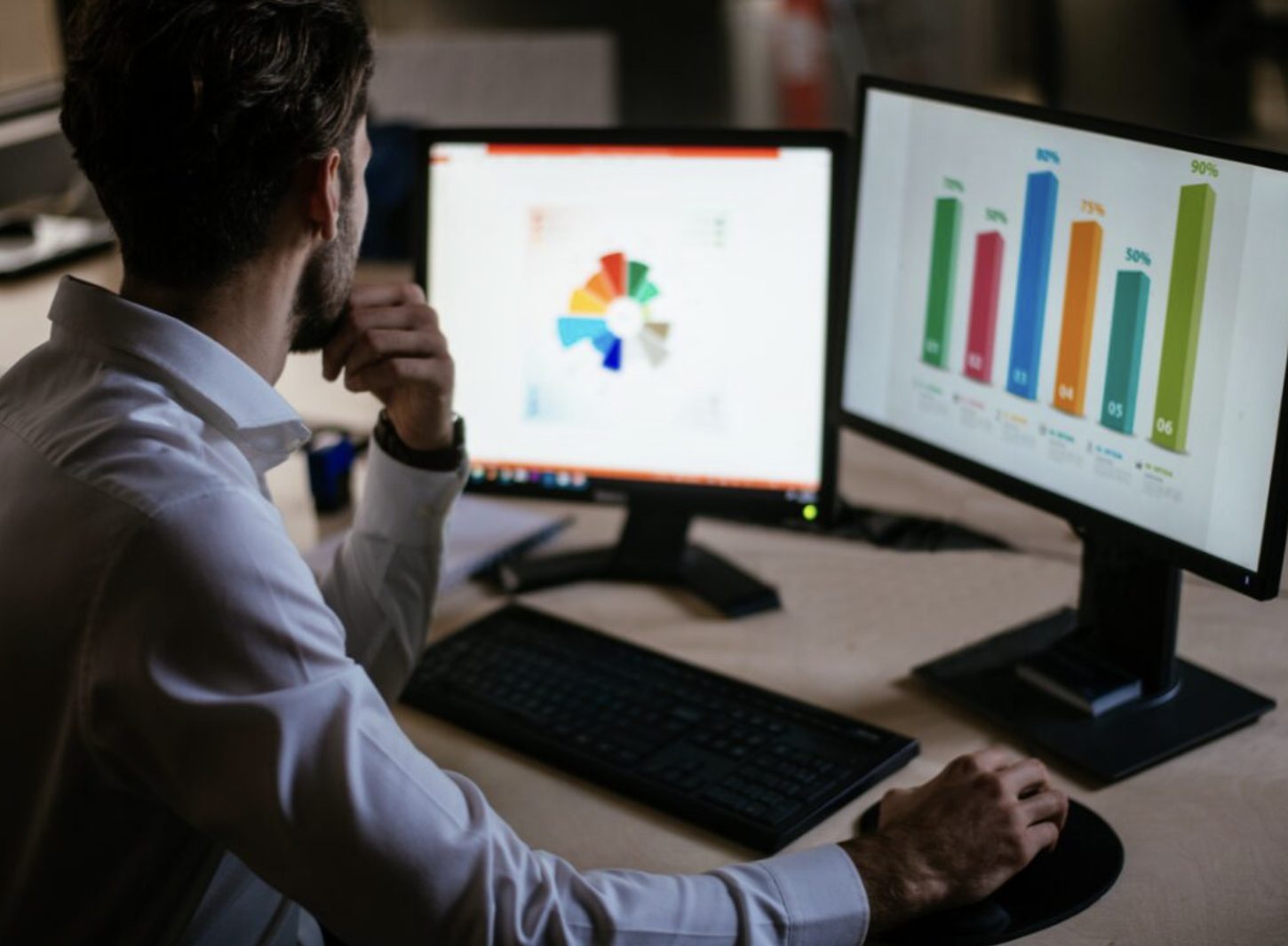 Man looking at computer screens showing revenue and other metrcis